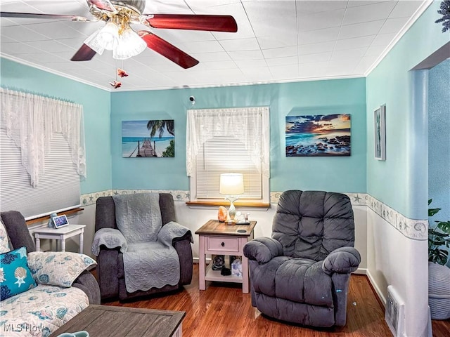 living area featuring hardwood / wood-style floors, ornamental molding, and ceiling fan