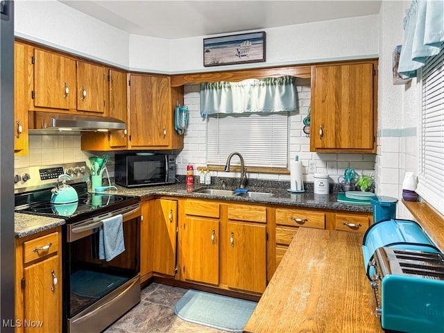 kitchen featuring tasteful backsplash, stainless steel range with electric stovetop, dark stone counters, and sink