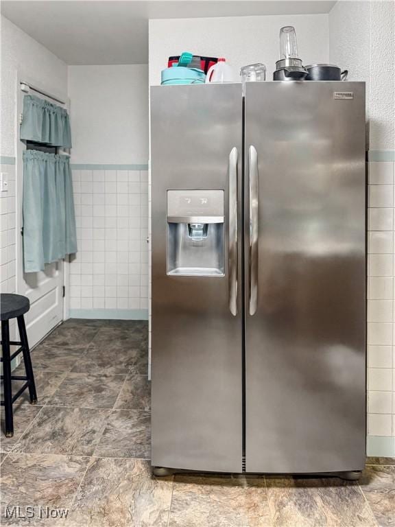 kitchen with stainless steel fridge and tile walls