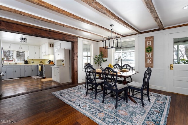 dining space featuring a notable chandelier, sink, dark hardwood / wood-style floors, and beamed ceiling