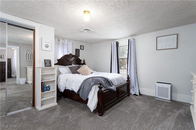 bedroom with a textured ceiling and dark colored carpet