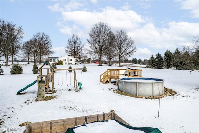 yard covered in snow featuring a playground