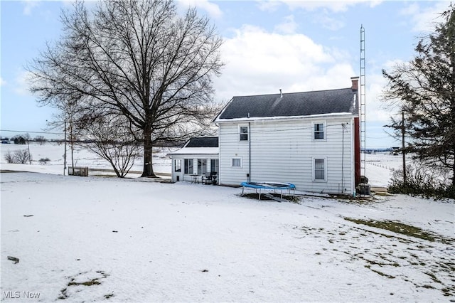 snow covered back of property with a trampoline