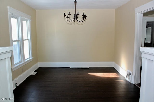 unfurnished dining area featuring dark wood-type flooring and a chandelier