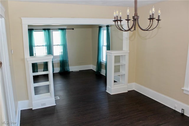 unfurnished dining area featuring a notable chandelier and dark hardwood / wood-style floors