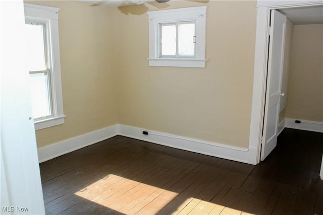 spare room featuring dark wood-type flooring, a wealth of natural light, and ceiling fan