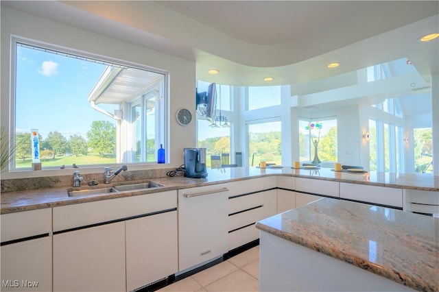 kitchen featuring white cabinetry, sink, light tile patterned floors, and light stone counters