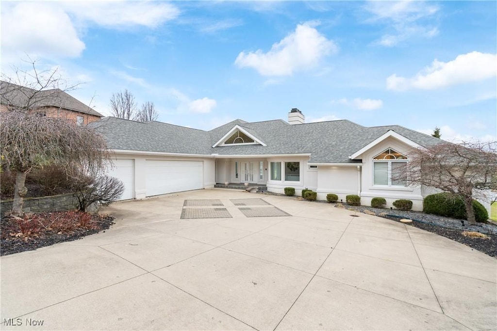 4182 Lochness Cir NW, Canton, OH 44718 - view of front facade with an attached garage, stucco siding, a chimney, concrete driveway, and a shingled roof