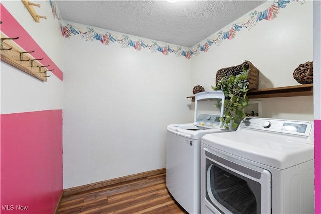 laundry room with dark wood-type flooring, a textured ceiling, and washer and clothes dryer