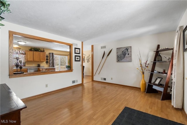 living room with a textured ceiling and light wood-type flooring