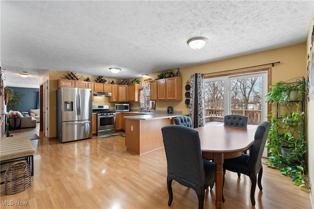 dining space featuring sink, light hardwood / wood-style flooring, and a textured ceiling