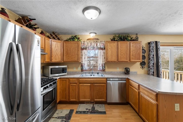 kitchen featuring stainless steel appliances, sink, light hardwood / wood-style flooring, and kitchen peninsula