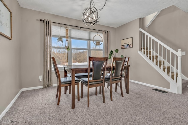 carpeted dining room featuring a chandelier