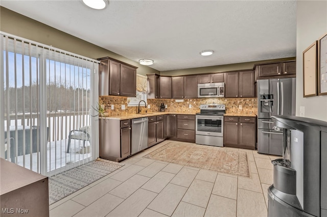 kitchen featuring light tile patterned flooring, appliances with stainless steel finishes, sink, and dark brown cabinets