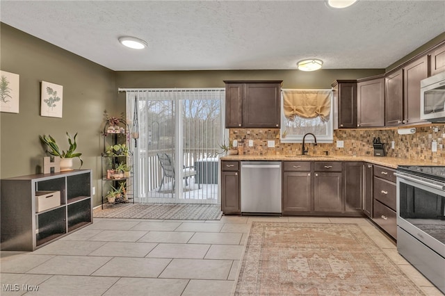 kitchen with dark brown cabinetry, sink, a wealth of natural light, and appliances with stainless steel finishes