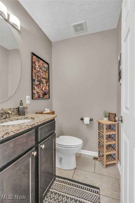 bathroom featuring vanity, tile patterned floors, a textured ceiling, and toilet