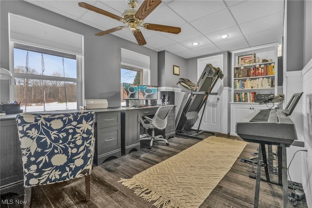 office area featuring ceiling fan, dark hardwood / wood-style flooring, and a drop ceiling