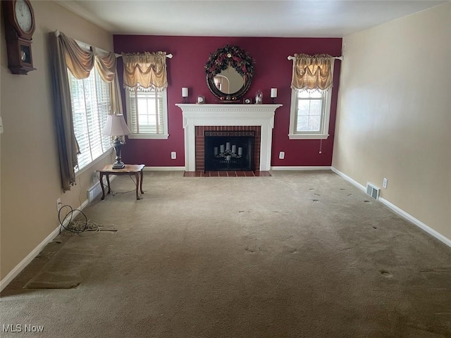 unfurnished living room with plenty of natural light, a brick fireplace, and carpet