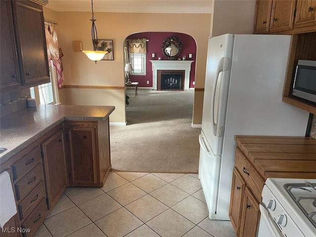 kitchen with a fireplace, light carpet, hanging light fixtures, and white range oven