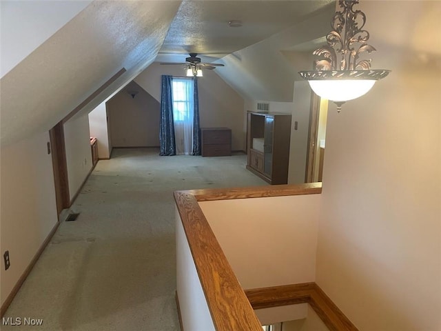 additional living space featuring lofted ceiling, ceiling fan, light colored carpet, and a textured ceiling