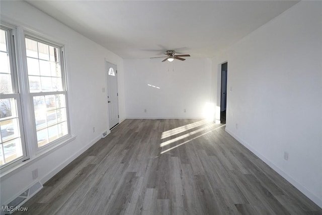 unfurnished living room featuring dark wood-type flooring and ceiling fan