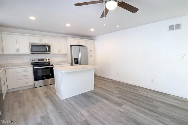 kitchen with backsplash, stainless steel appliances, a center island, and white cabinets