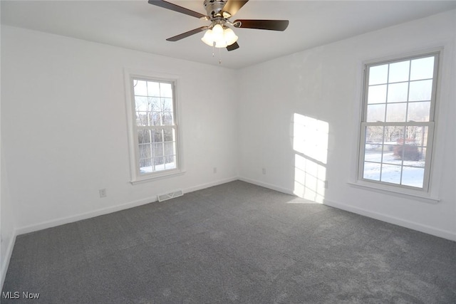 empty room with plenty of natural light, ceiling fan, and dark colored carpet