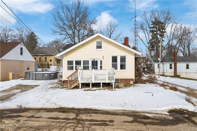 snow covered back of property with a wooden deck