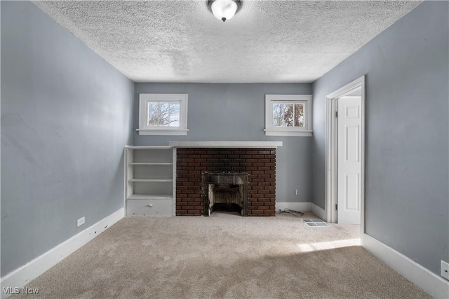 unfurnished living room featuring light colored carpet, a brick fireplace, and a textured ceiling