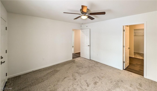 unfurnished bedroom with ceiling fan, a closet, carpet, and a walk in closet