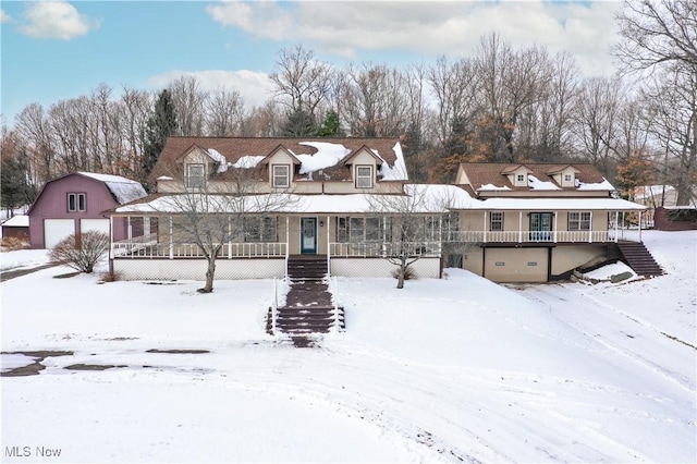 snow covered house featuring a garage and covered porch