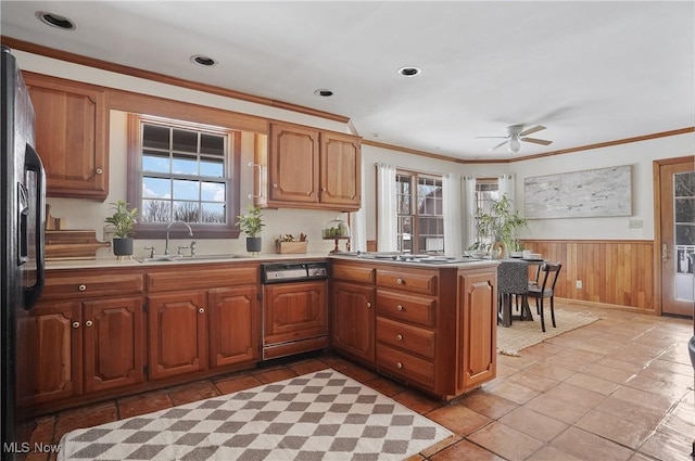 kitchen featuring black fridge with ice dispenser, sink, wooden walls, stainless steel gas stovetop, and paneled dishwasher