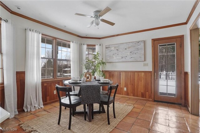 dining area with ornamental molding, ceiling fan, and wooden walls