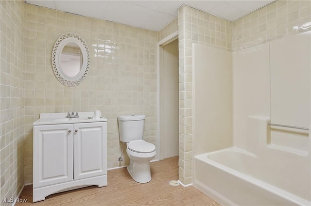 bathroom with vanity, hardwood / wood-style floors, tile walls, and toilet