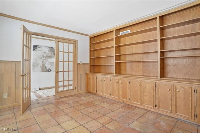 interior space with built in shelves, wooden walls, ornamental molding, and french doors