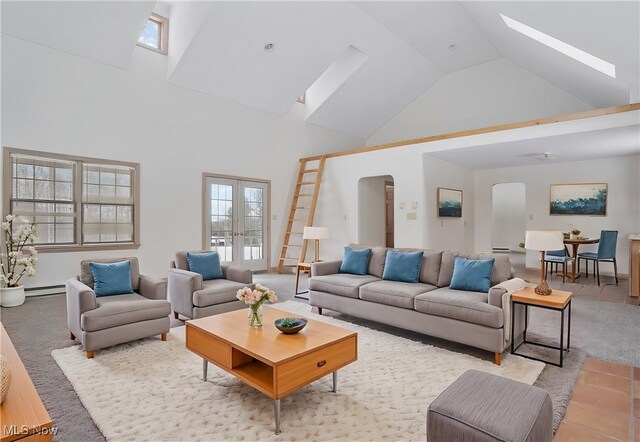 living room with a skylight, a baseboard radiator, high vaulted ceiling, and french doors