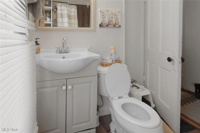 bathroom featuring vanity, toilet, hardwood / wood-style floors, and radiator heating unit