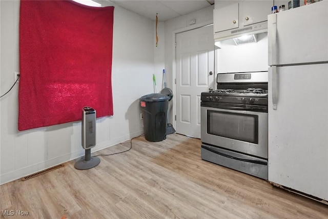 kitchen featuring white refrigerator, stainless steel range with gas cooktop, and light wood-type flooring