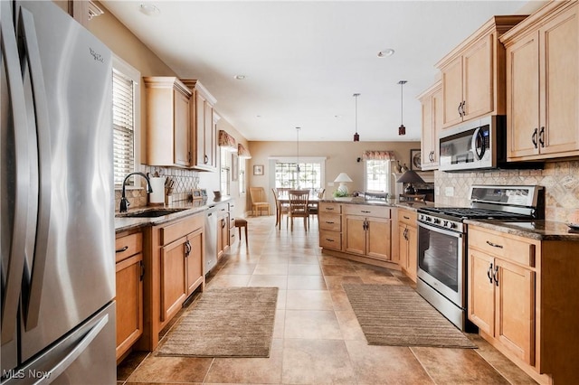 kitchen with sink, appliances with stainless steel finishes, hanging light fixtures, backsplash, and kitchen peninsula