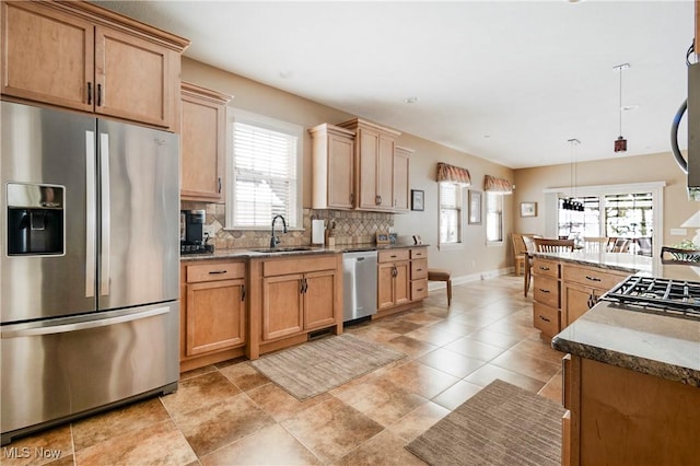 kitchen featuring sink, stone countertops, decorative light fixtures, stainless steel appliances, and backsplash