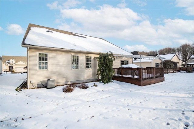 snow covered house featuring central AC and a deck