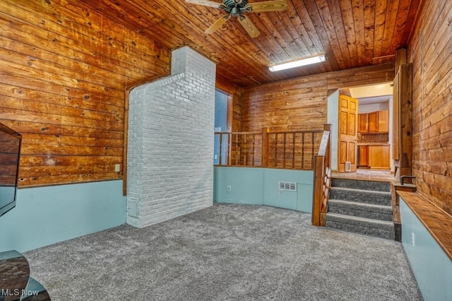 unfurnished living room featuring wooden ceiling, ceiling fan, and carpet