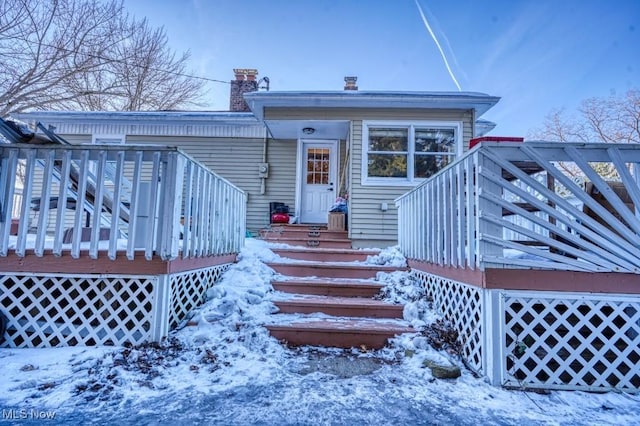 snow covered rear of property with a deck