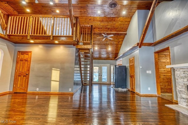 unfurnished living room featuring hardwood / wood-style flooring, high vaulted ceiling, a stone fireplace, wooden ceiling, and french doors