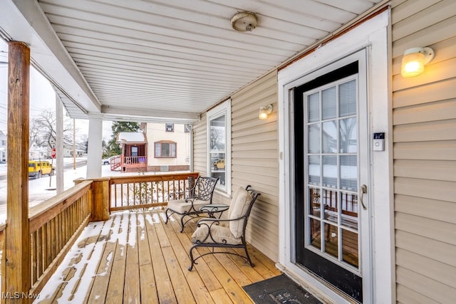 snow covered deck featuring a porch