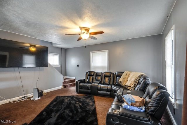 living room featuring ceiling fan, dark carpet, and a textured ceiling