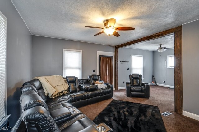 living room with a textured ceiling, ceiling fan, and carpet flooring