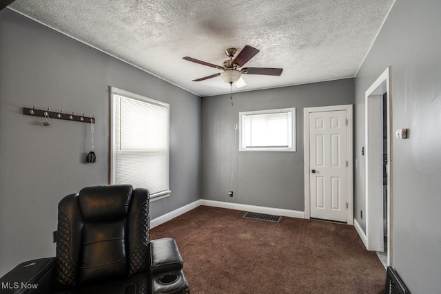 sitting room with ceiling fan, dark carpet, and a textured ceiling