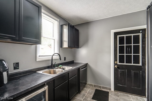 2743 12th St SW, Canton, OH 44710 - kitchen with stainless steel dishwasher, a sink, dark cabinets, dark countertops, and a textured ceiling