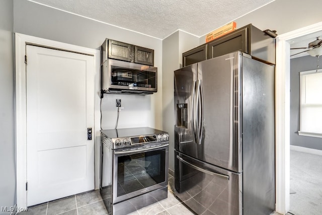 2743 12th St SW, Canton, OH 44710 - kitchen with appliances with stainless steel finishes, a textured ceiling, dark brown cabinets, light tile patterned floors, and baseboards